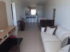 Apart Canoa Quebrada vista mar- condominio fechado في أراكاتي: غرفة معيشة مع أريكة بيضاء ومطبخ