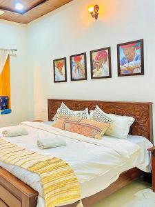 a bedroom with a large bed with four pictures on the wall at Jasmer Haveli in Jaisalmer