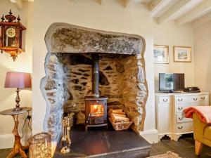 a stone fireplace in a living room with a stove at 1 Penygroes in Penmachno