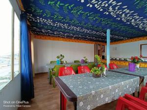a dining room with tables and chairs and a blue ceiling at Blue Chill Cottage Pangong in Lukung