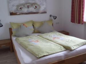 ein Bett mit gelben Laken und Blumen darauf in der Unterkunft Haus Regenbogen in Pertisau
