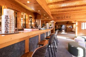 a bar in a restaurant with wooden ceilings and chairs at Le Chalet d'Antoine - Centre de Megève in Megève