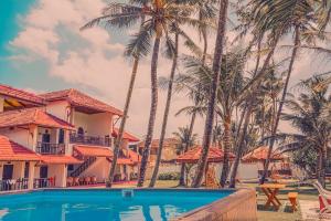 a view of a resort with palm trees and a swimming pool at MANTA RAY MANOR HAVEN -Nestled on Sri Lanka's Southern Coast, offers Luxurious rooms with Ocean, Garden, & Pool Views, a Private Beach, Ocean-View Pool with a Jacuzzi, & Event Hosting & more, your Perfect Escape for Relaxation & Unforgettable Moments in Ahangama