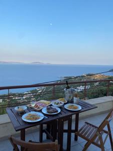 einen Tisch mit Tellern aus Essen auf einem Balkon in der Unterkunft Villa Aurora with magnificent view of the Aegean sea in Ambelón