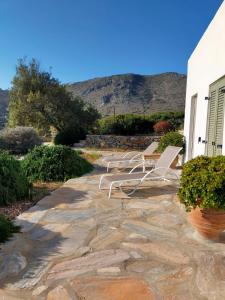 2 sillas blancas de jardín sentadas en un patio de piedra en Amorgos Villa Handras / Main villa, en Amorgós