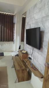 a living room with a flat screen tv on a wall at hotelbhavya in Ahmedabad