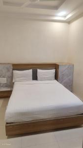 a bed in a white room with a wooden headboard at hotelbhavya in Ahmedabad