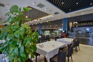 a restaurant with white tables and chairs and a plant at La Flora House Hotel in Kocaeli