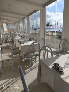 a dining room with tables and chairs and windows at HOTEL PARADISE in Porto Cesareo