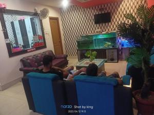 twee mensen zitten op stoelen in een woonkamer met een aquarium bij Goroomgo Blue Bell Bhubaneswar in Bhubaneshwar
