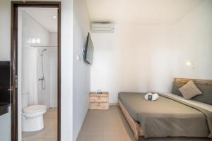 a small bedroom with a bed and a toilet at Gelatik Bed And Breakfast in Seminyak