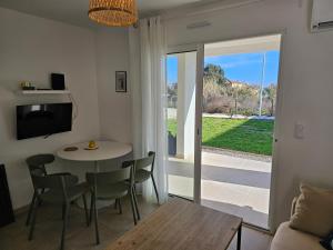 ein Wohnzimmer mit Tisch und Stühlen und einem Fernseher in der Unterkunft Superbe appartement vue mer terrasse couverte face à la mer in Linguizzetta