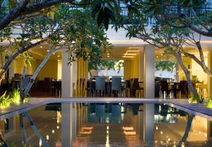 una piscina en el vestíbulo de un hotel con mesas y sillas en Hotel Santika Kuta, en Kuta