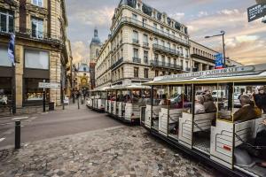 two trolley trolleys filled with people on a city street at PETIT CROIX in Rouen