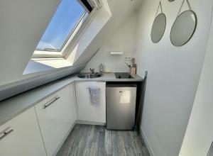 a small white kitchen with a sink and a window at PETIT CROIX in Rouen
