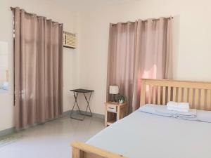 - une chambre avec un lit et une fenêtre avec des rideaux dans l'établissement Grae’s Apartelle, à Moalboal