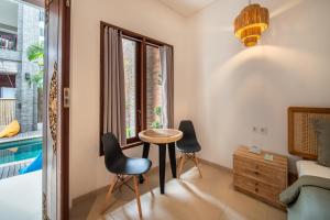 a living room with a table and chairs and a pool at Gelatik Bed And Breakfast in Seminyak