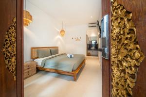 a bedroom with a bed and a television in it at Gelatik Bed And Breakfast in Seminyak