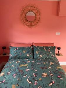 uma cama com um edredão verde e um espelho em Cabin de la Paix em Hadleigh