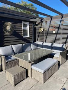 a patio with a glass table and cushioned chairs at Cabin de la Paix in Hadleigh