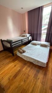 2 łóżka w pokoju z drewnianą podłogą i oknem w obiekcie Kleos Villa Baguio City w mieście Tuding
