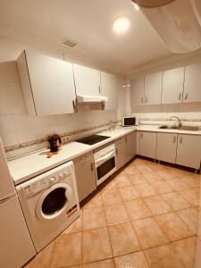 a kitchen with white cabinets and a washer at Vivienda 2 dormitorios Churriana-Aeropuerto in Málaga