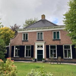 a red brick house with a black roof at De Lindehoeve Appartement de Pompestraat in Vledder
