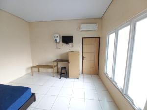 Zimmer mit einem Bett, einem Schreibtisch und einem Kühlschrank in der Unterkunft OYO LIFE 93634 Penginapan D'palinggihan Syariah in Cirebon