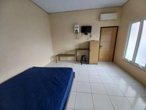 a bedroom with a bed and a room with a refrigerator at OYO LIFE 93634 Penginapan D'palinggihan Syariah in Cirebon