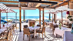 a restaurant with tables and chairs with the ocean in the background at Tranquil Haven in Cape Town