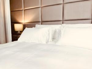 a white bed with a padded headboard and white pillows at Tranquil Haven in Cape Town