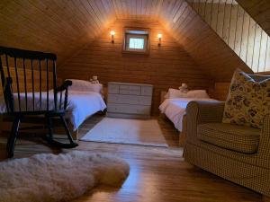 a attic room with two beds and a chair at chalupa Komora in Lužná