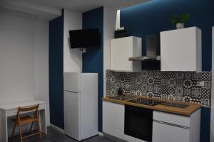 a kitchen with white appliances and a blue wall at Poseidon's refuge in La Spezia