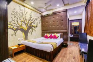 a bedroom with a bed with a tree mural on the wall at The Ashoka Hotel in Indore