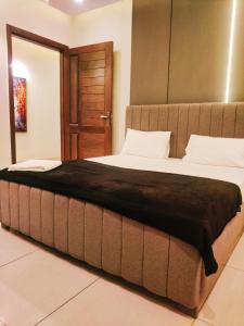 Cette chambre comprend un grand lit et une porte en bois. dans l'établissement Deluxe Luxury Apartment, à Rawalpindi