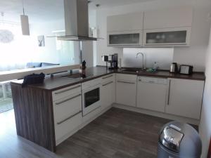 a kitchen with white cabinets and a wooden floor at Ferienwohnung am Wildpark HDH in Heidenheim