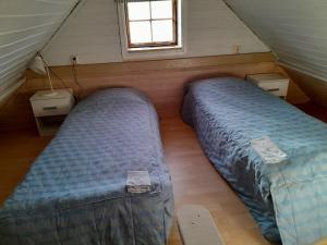 two beds in a attic bedroom with a window at Lotta´s Cottage in Rimbo