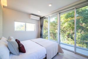 um quarto com uma cama branca e janelas grandes em RIVERSIDE TERRACE OKINAWA KADENA em Kadena