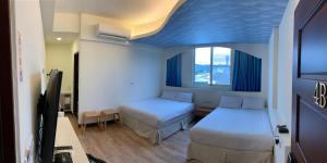 una camera d'albergo con due letti e una tv di 台東1314電梯民宿 a Città di Taitung