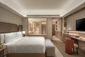 a hotel room with a large bed and a television at InterContinental Wuxi Taihu New City in Wuxi