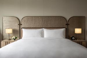 a large bed with white pillows and two lamps at InterContinental Wuxi Taihu New City in Wuxi