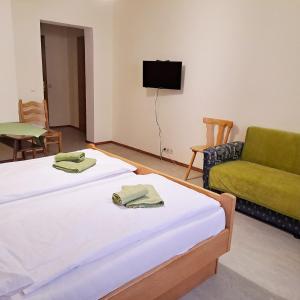 Duas camas num quarto com um sofá e uma televisão em Almgasthof Spitzer em Sankt Stefan ob Leoben