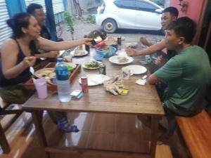 um grupo de pessoas sentadas ao redor de uma mesa comendo comida em Casa Minha Backpackers Hostel em Dili
