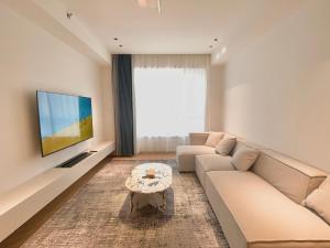 ein Wohnzimmer mit einem Sofa und einem TV in der Unterkunft ZHome-Count luxury apartment in Shanghai