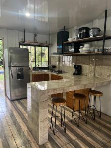a kitchen with a counter with stools and a refrigerator at Villa bonita in Puerto Jiménez
