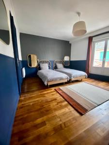 2 letti in una camera con pareti blu e pavimenti in legno di Charmant gîte au bord de la Sarthe - 3 chambres - 6 personnes a Fillé