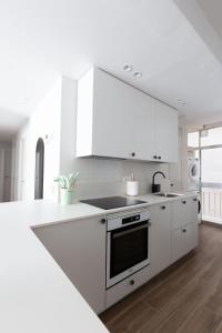 a white kitchen with white cabinets and a stove top oven at Exclusive cozy Atocha apartment in Madrid