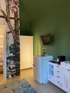 Habitación con nevera blanca y pared verde. en YOLE Affittacamere en Empoli