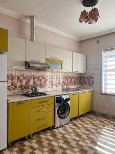 a kitchen with yellow cabinets and a washing machine at Miracle Gabala villa in Gabala
