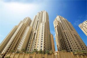 three tall buildings with palm trees in front of a blue sky at Pure Sand - Luxury Hostel JBR Dubai in Dubai